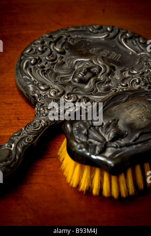 Stillleben mit ein antiker Pinsel und Hand-Spiegel mit einem reich verzierten Design einer Frau mit langen Locken der Haare. Stockfoto