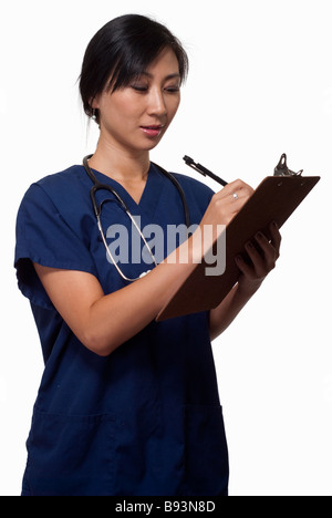 Junge Brünette Asiatin Gesundheitswesen Arbeitnehmer tragen blaue scheuert auf Karte schreiben Stockfoto