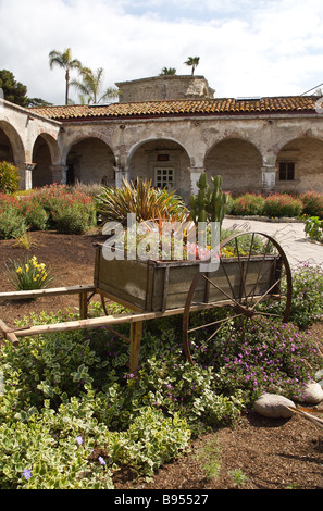 Leiterwagen mit Blumen mit Mission Gebäude im Hintergrund, Mission San Juan Capistrano Stockfoto