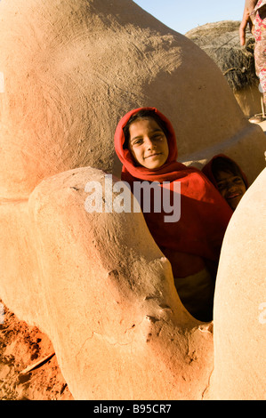 Eine Frau lächelt aus ihrer Heimat, schöne Wüste Architektur sehen in den Dörfern der Wüste Regionen von Rajasthan, Indien Stockfoto