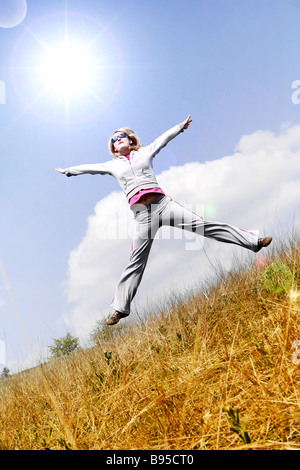 Glückliche Frau springen gegen blauen Himmel Stockfoto