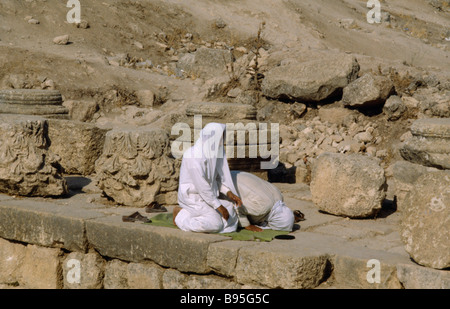 Jordanien Nahost Jerash zwei muslimische Männer kniend im archäologischen Ruinen in Richtung Mekka beten. Stockfoto