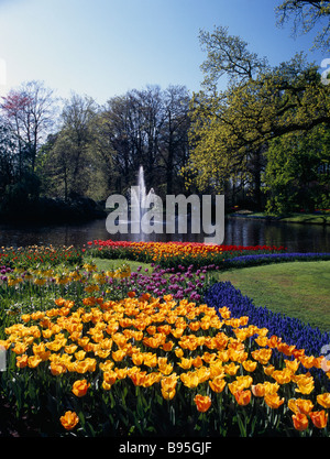 Niederlande, Zuid-Holland, Lisse, Keukenhof Gärten. Brunnen im See, umgeben von Bäumen und Displays von Frühlingsblumen. Stockfoto