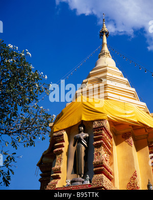 THAILAND Norden Chiang Mai Standing Buddha-Statue unter goldene Chedi in golden orange Seide gehüllt und hing mit Lichtern. Stockfoto