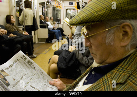 JAPAN Honshu Tokio Tokyo Metro älteren japanischen Mann tragen Tweed Mütze und Jacke, eine Zeitung lesen Stockfoto