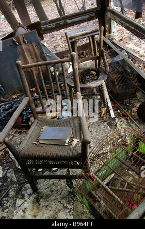 Stühle, Möbel, Vogelkäfig und Bücher sind über ein ausgeschlossenes Haus verstreut, nachdem Feuer das leere leer stehende Haus beschädigt. Stockfoto