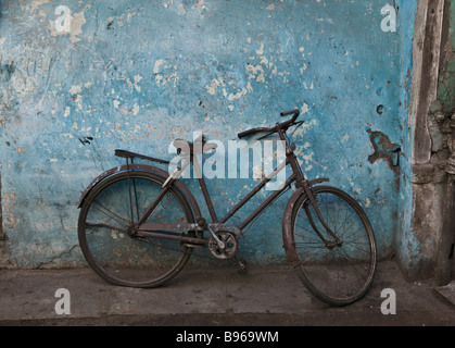 Einer alten, rostigen Fahrrad gelehnt eine blaue Wand in der Altstadt von Ahmedabad, Indien Stockfoto