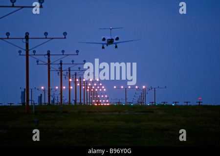 Düsenverkehrsflugzeug auf Ansatz über Start-und Landebahn Lichter am DFW International Airport unter bewölktem Himmel aber klarem Wetterbedingungen Stockfoto