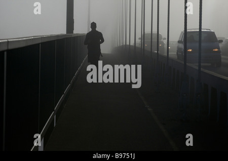 Mann, der im Nebel auf der Lions Gate Bridge läuft, Vancouver, British Columbia Stockfoto