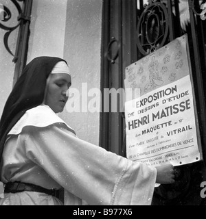 1951, historische, eine katholische Nonne stellt ein Poster über eine Ausstellung des französischen Künstlers Henri Matisse Designs für die Chapelle du Rosaire in Vence. Stockfoto