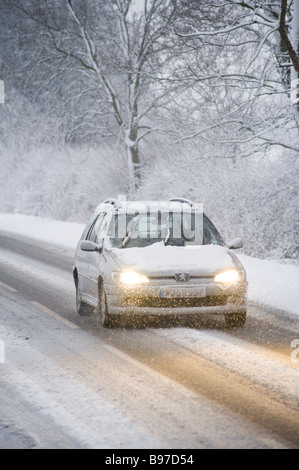 Einsamer Wagens auf dem Schnee bedeckt Straße im grünen an einem Wintertag in england Stockfoto