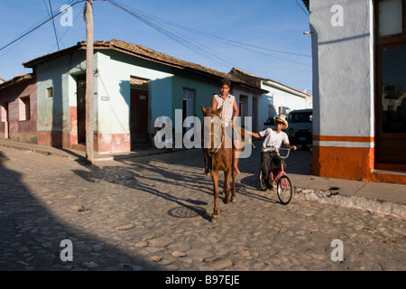 Ein Junge auf einem Fahrrad bekommt einen Aufzug von einem Freund auf einem Pferd in Trinidad, Kuba Stockfoto