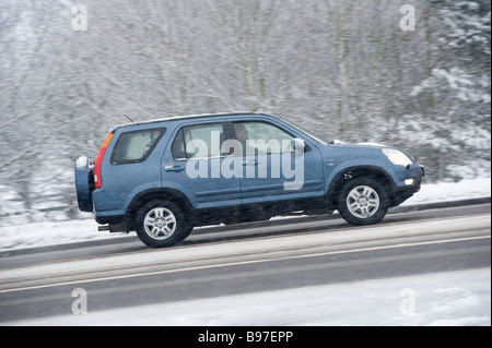 Seitenansicht eines blauen Honda Hrv 4 x 4 Autos fahren entlang einer Schnees bedeckt Straße an einem Wintertag in england Stockfoto