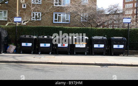 Eine Straßenseite Recyclinghof einschließlich Altglascontainer und Container für Altkleider und Schuhe in Victoria, London. Stockfoto