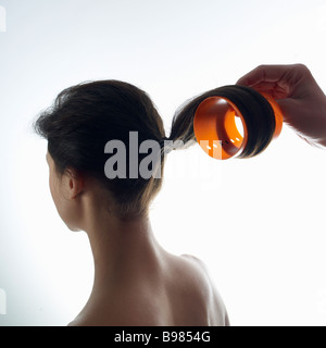 Junge Frau curling Haare mit Haar-Walze, Nahaufnahme Stockfoto