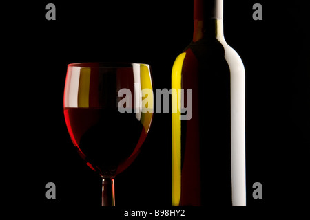 Rotwein, Glas und Flasche auf schwarz. Stockfoto