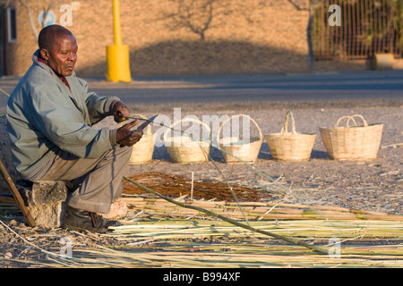 Ein Mann webt Körbe aus Rohr und Schilf am Straßenrand in der Stadt Upington in South Africas Northern Cape Provinz Stockfoto