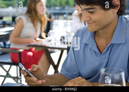 Junger Mann sitzen im Café im Freien, mit Handy Stockfoto