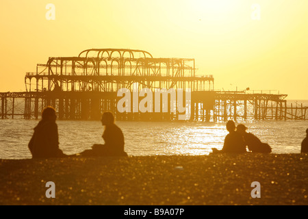 Menschen sind gegen Sonnenuntergang Silhouette, wie sie am Strand in Brighton, England, 13. März 2007 sitzen. Foto von Akira Suemori Stockfoto