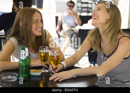 Zwei junge Freundinnen mit Glas Bier am Straßencafé sitzen Stockfoto