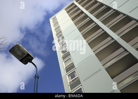 Ein 60er Jahre Wohnblock angesehen in Richtung der lückenhaft wolkenverhangenen Himmel mit einem Laternenpfahl in einer Ecke Stockfoto