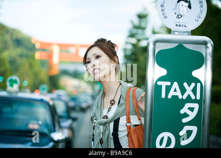 Junge Frau wartet am Taxistand Stockfoto