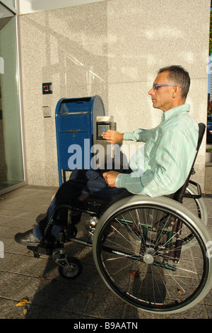 voller Länge Profil Seite Ansicht städtebauliches Portrait eines behinderten Menschen in einem Rollstuhl mit einem automatisierten Türautomatik Textfreiraum Stockfoto