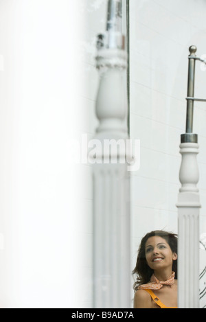 Junge Frau, die durch Fenster, Lächeln Stockfoto