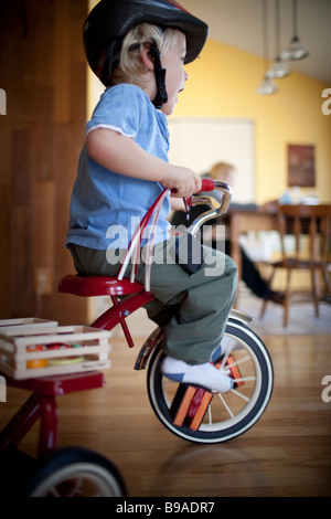 Kleinkind Reiten ein Dreirad rund um das Haus Stockfoto
