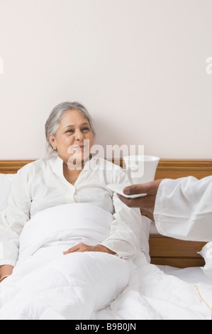 Mann, hält Kaffee-Tablett in der Nähe einer Frau auf dem Bett liegend Stockfoto