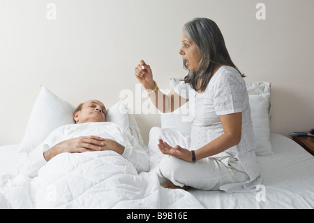 Frau, die Überprüfung eines Mannes Temperatur im Schlafzimmer Stockfoto