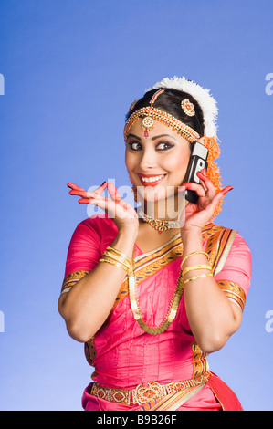 Telefonieren mit einem Handy in und Durchführung von Bharatnatyam Tänzerin Stockfoto
