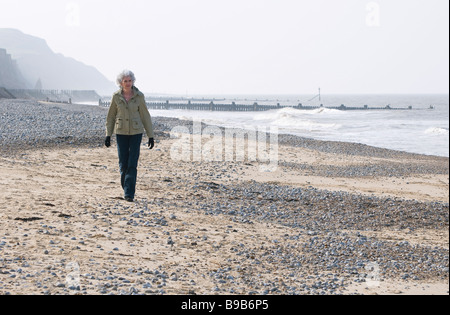 einzelne, einsame Reife Frau zu Fuß am Strand Stockfoto