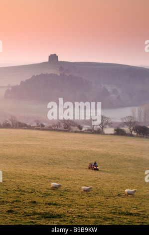 Landwirt Aufrundung Schafe in der Morgendämmerung unter Schatten der St. Catherines Chapel, Dorset Stockfoto
