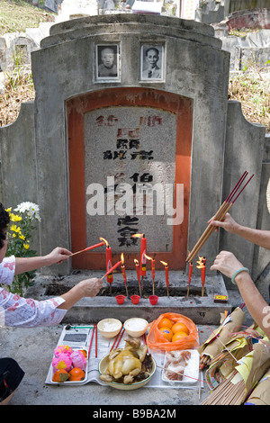 Angebote und Aufleuchten des Josticks auf einem Grabstein während Qing Ming in Malaysia, Süd-Ost-Asien Stockfoto