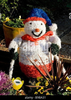 Künstlicher Schneemann mit Skiern und blauen Pudelmütze im Garten Stockfoto