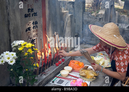 Angebote und Aufleuchten des Josticks auf einem Grabstein während Qing Ming in Malaysia, Süd-Ost-Asien Stockfoto