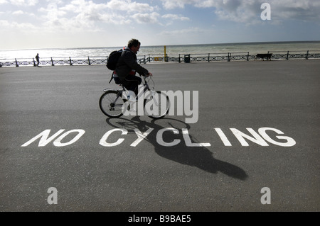 Ein Radfahrer ignorieren ein "No Radfahren Schild am Strand von Brighton und Hove. Stockfoto