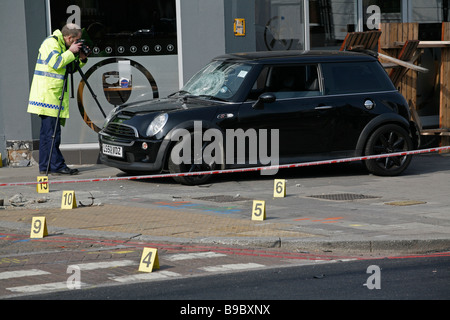 Forensische Polizei Beweisaufnahme nach ein Verkehrsunfall ein Auto auf dem Bürgersteig, auf Clapham High Street, South London verlässt. Stockfoto