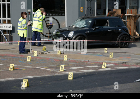 Forensische Polizei Beweisaufnahme nach ein Verkehrsunfall ein Auto auf dem Bürgersteig, auf Clapham High Street, South London verlässt. Stockfoto