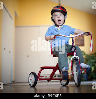 Kleinkind Reiten ein Dreirad rund um das Haus Stockfoto