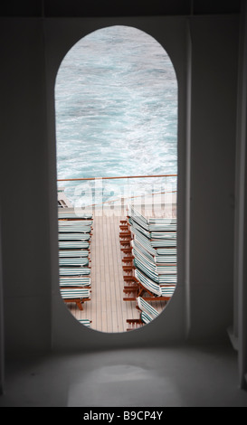 Reihen von Liegestühlen auf dem Deck der Queen Mary 2, angezeigt durch eine Öffnung Stockfoto