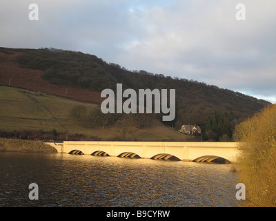 Blick über Ladybower Vorratsbehälter zu Yorkshire Brücke Viadukt (auf A57 Snake Pass Straße) beleuchtet durch die Wintersonne Stockfoto