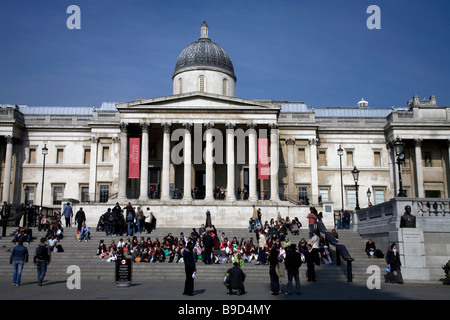 Touristen und Schüler über die Schritte auf dem Trafalgar Square vor der Natiional Gallery in London England Stockfoto