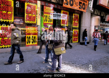 New York geht aus dem Geschäft Liquidation Verkauf.Touristen schauen sich eine Karte auf der Straße vor dem schließenden Geschäft am Broadway in Midtown Manhattan USA an Stockfoto