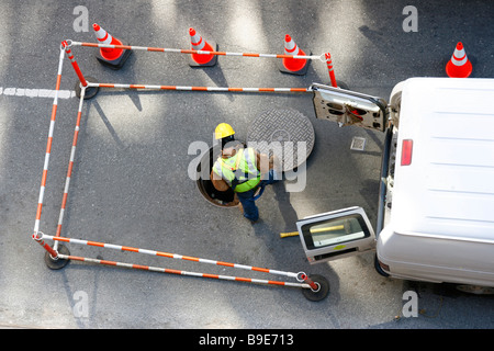 Instandhalter Dienstprogramm sieht in offenen Schacht auf der Straße. Stockfoto