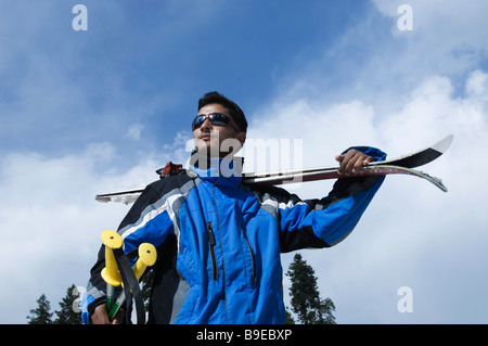 Mann mit Ski auf seinen Schultern, Gulmarg, Jammu und Kaschmir, Indien Stockfoto