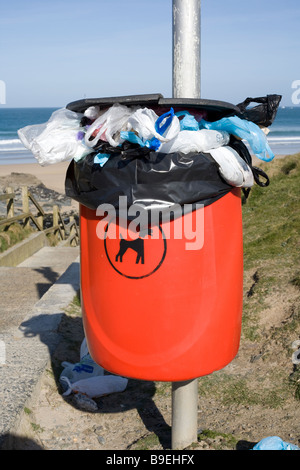 Rote Hund Abfallbehälter voll und überfüllt mit Taschen, in der Nähe von einem britischen Strand. Stockfoto