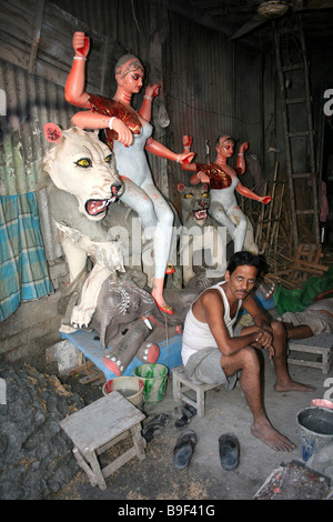 Artisan sitzt in seiner Werkstatt neben semi-bemalte Statue von Durga reitet Lion, Töpfer-Markt, Kumortuli, Kolkata Stockfoto