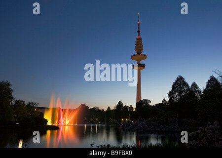 Beleuchtete Brunnen in der Nähe Fernmeldeturm vor düsteren Himmel, Hamburg, Deutschland Stockfoto